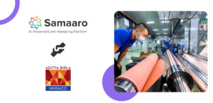 A worker adjusts machinery in a modern industrial setting, with vibrant rolls of material in focus and equipment in the background.